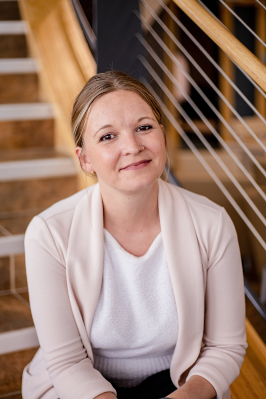 Stephanie Mason headshot sitting on stairs smiling
